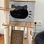 cat, black_cat, cat_tree, scratching_post, cat_cubby, furniture, indoor, pet, cozy, wood_floor, plug_socket, cord, fuzzy_bed, worn, relaxed, animal, household, cute, resting, pet_accessory