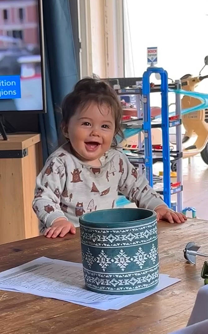 Lenny participe au concours pour gagner de l'argent avec cette photo : child, coffee_cup, cup, dishware, drinkware, flooring, fun, happy, leisure, person, recreation, serveware, sitting, smile, t_shirt, table, tableware, television, toddler, water