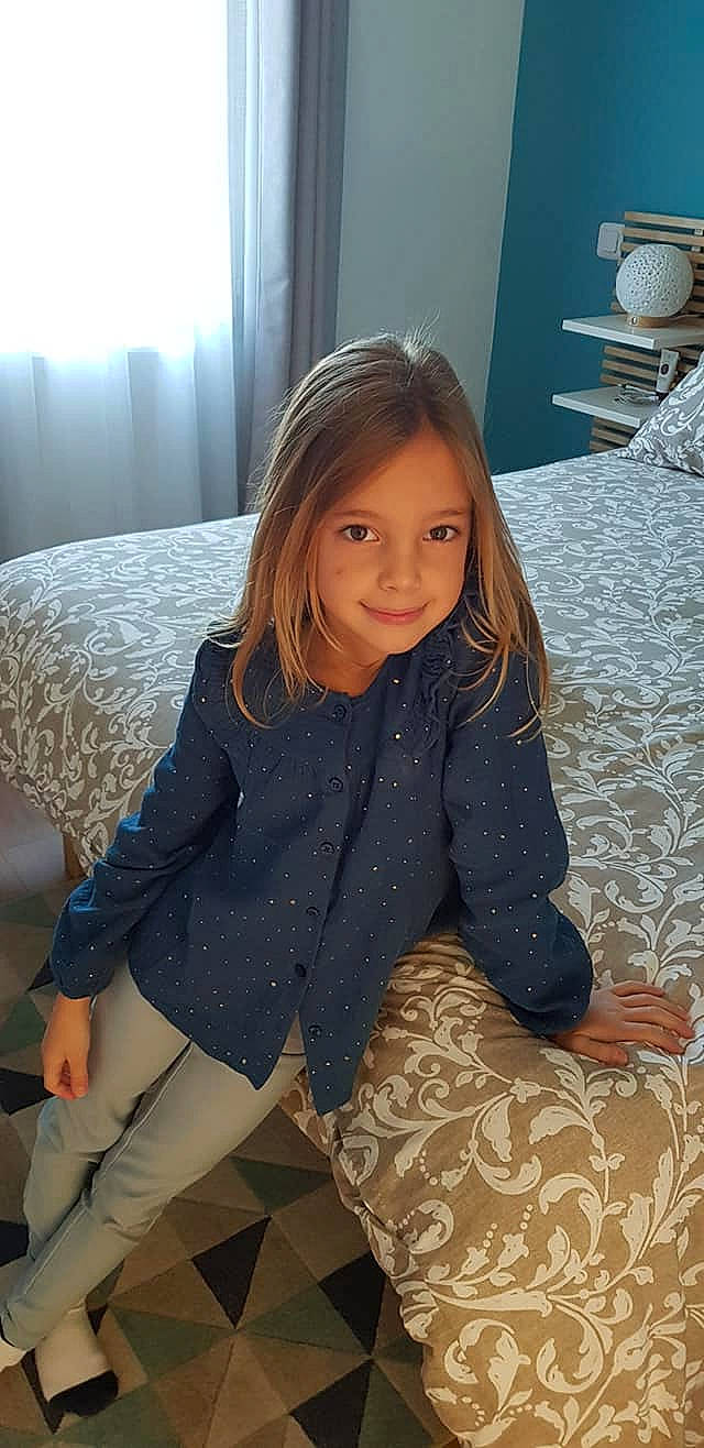 Lou participe au concours pour gagner de l'argent avec cette photo : child, clothing, comfort, facial_expression, floor, flooring, fun, hair, happy, human_leg, joy, knee, leg, long_hair, mammal, person, skin, sleeve, smile, standing