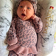Xiomara joined the competition — help win amazing prizes! baby, infant, headband, bow, pink_clothing, leopard_print, knitwear, cushion, marble_pattern, surprised_expression, lying_down, indoor, soft_texture, child, newborn, person, cute, cozy, comfortable, portrait