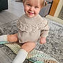 child, toddler, smiling, sitting, indoors, sweater, socks, shoes, rug, floor, blanket, knitted, home, happy, cute, person, face, hair, toy, candid