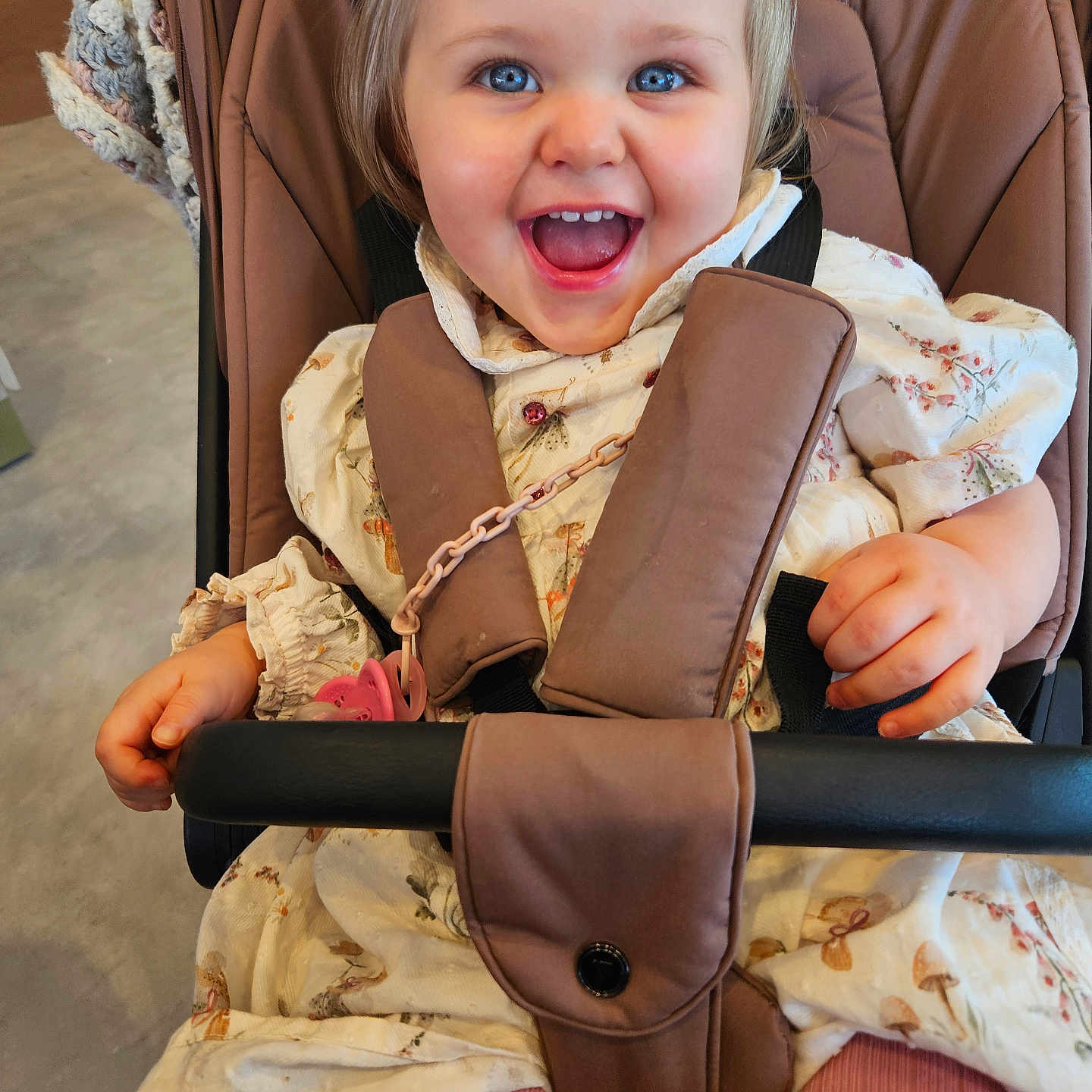 Nyla is registered to the contest to win money with this photo: baby, baby_accessory, blue_eyes, child, clothing, cute, dress, face, hand, happy, indoor, infant, joy, person, pink_tights, seatbelt, smiling, stroller, toddler, young
