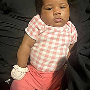 Amira joined the competition — help win amazing prizes! baby, infant, child, pink_clothing, mittens, checkered_pattern, portrait, cute, indoors, sitting, young_child, skin, face, head, expressionless, person, apparel, short_sleeves, pants, resting