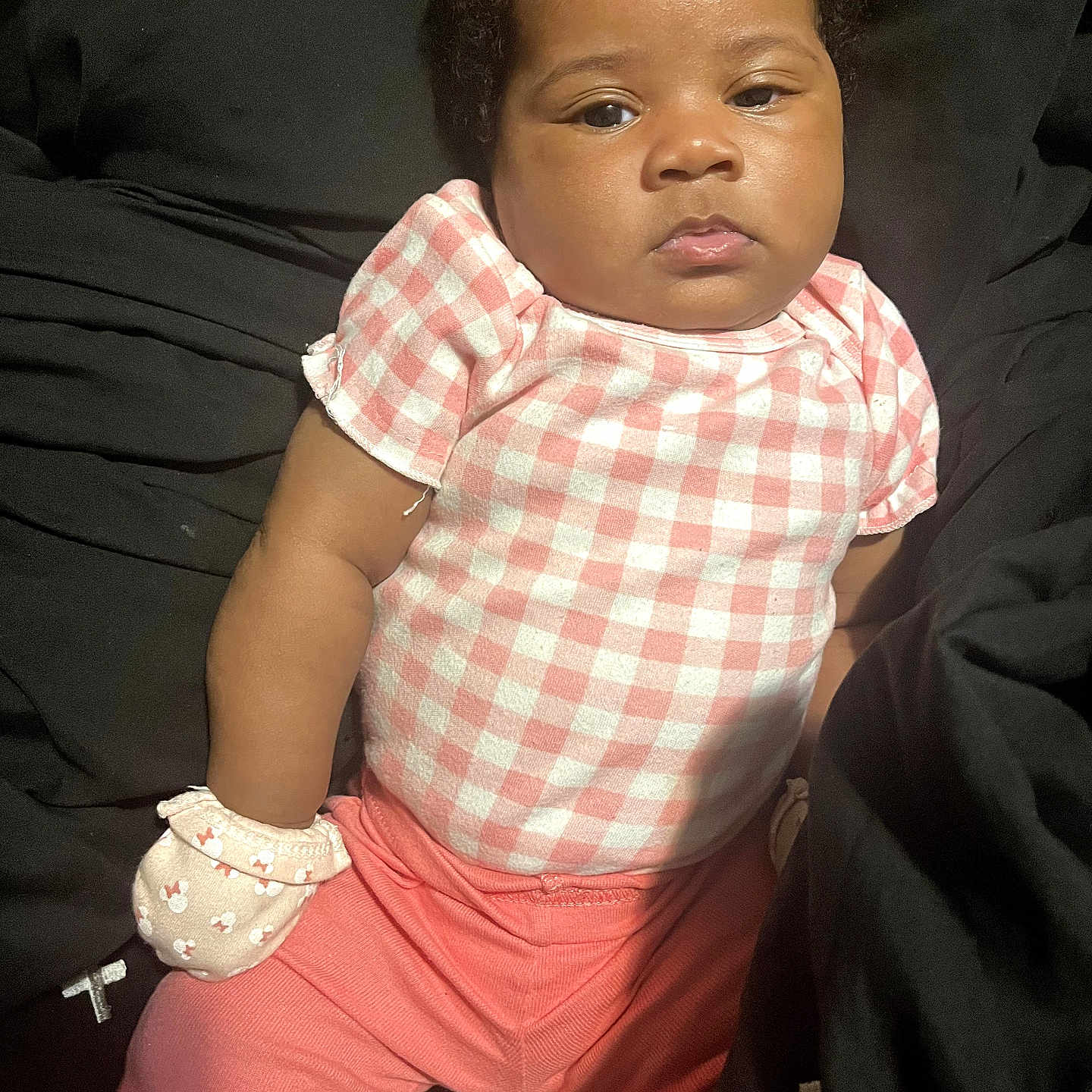 Amira joined the competition — help win amazing prizes! baby, infant, child, pink_clothing, mittens, checkered_pattern, portrait, cute, indoors, sitting, young_child, skin, face, head, expressionless, person, apparel, short_sleeves, pants, resting