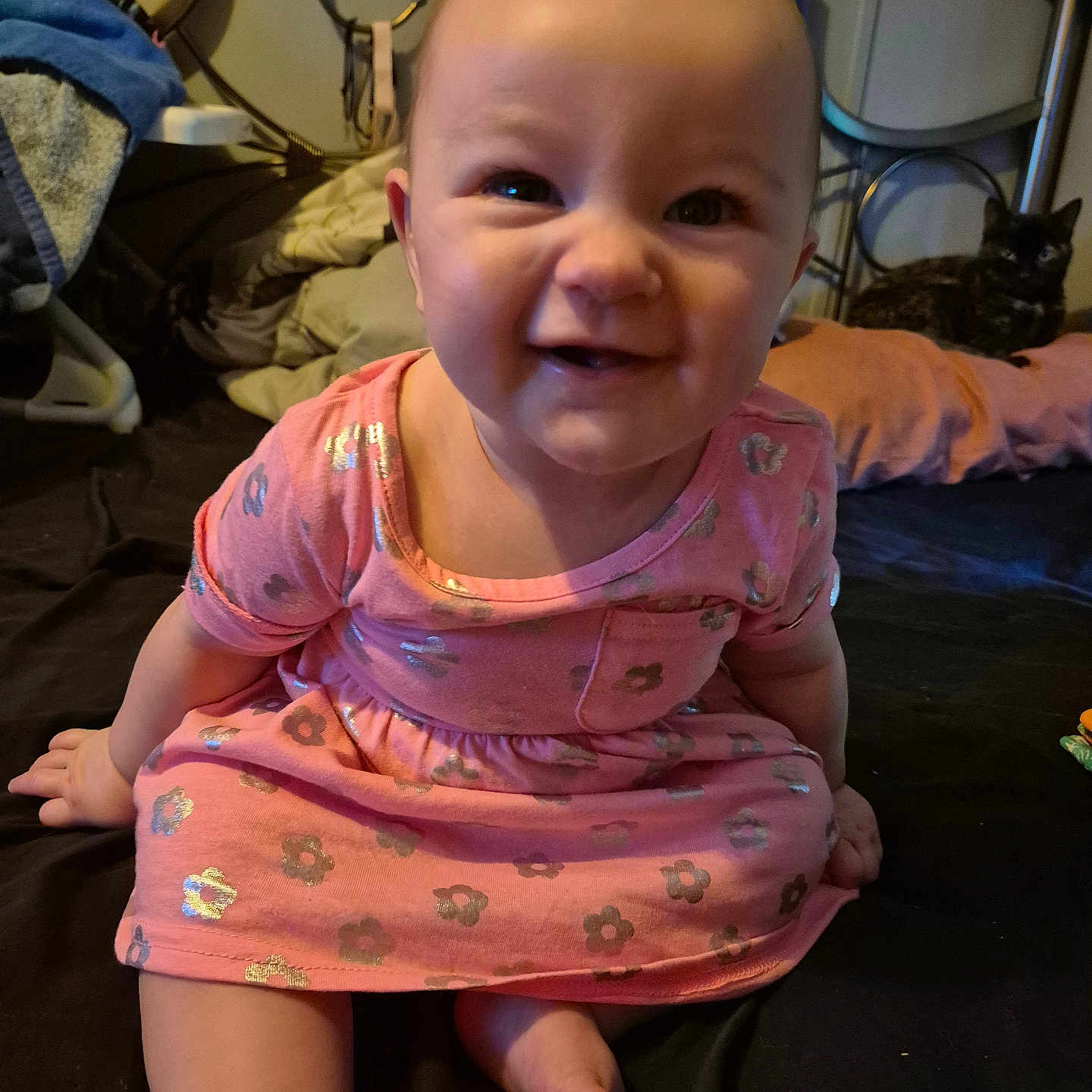 Samara is registered to the contest to win money with this photo: animal, baby, bed, blanket, cat, child, cute, face, foot, hand, happy, headboard, home, indoor, infant, person, pillow, pink_dress, sitting, smiling