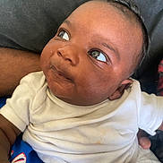 Kyaie is registered to the contest to win money with this photo: adult, baby, casual, child, closeup, curious, expression, eyes, face, hand, holding, indoor, infant, looking_away, onesie, person, portrait, skin, soft_light, white_clothing