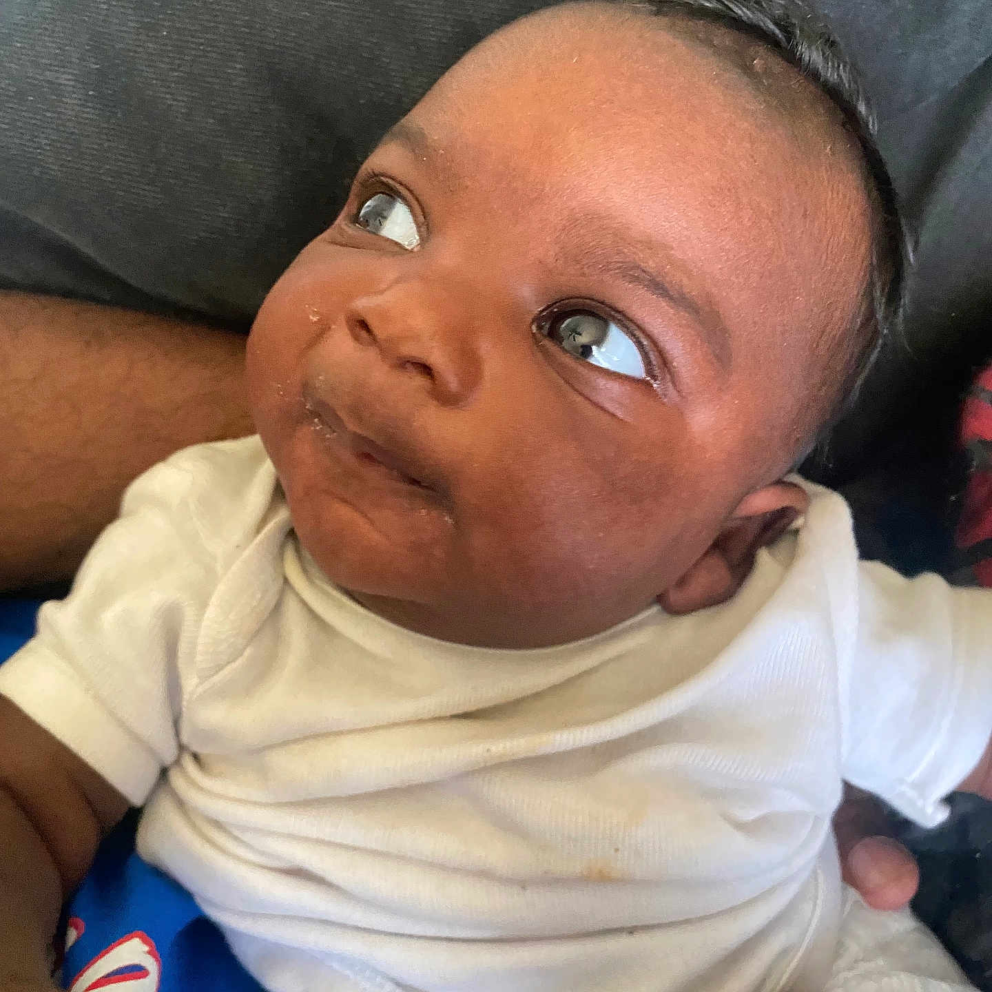 Kyaie is registered to the contest to win money with this photo: adult, baby, casual, child, closeup, curious, expression, eyes, face, hand, holding, indoor, infant, looking_away, onesie, person, portrait, skin, soft_light, white_clothing