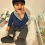 baby, child, cap, clothing, changing_pad, diapers, furniture, indoor, infant, person, playful, shoe, sitting, smile, toy, warm_clothes, young_child, basket, curious, cozy