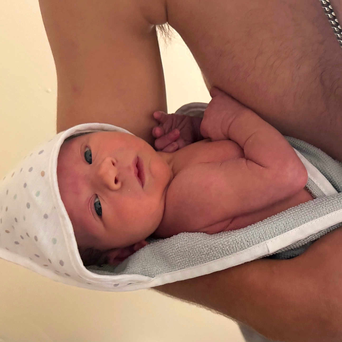 Beau joined the competition — help win amazing prizes! newborn, baby, infant, towel, hooded_towel, arm, skin, person, necklace, cross, bare_chest, holding, close_up, indoors, cute, small, sleepy, resting, human, portrait