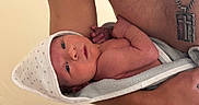 Beau joined the competition — help win amazing prizes! adult, baby, bare_chest, closeup, cross, cute, hand, holding, hooded_towel, human, indoor, infant, necklace, newborn, person, portrait, skin, small, towel, wrapped
