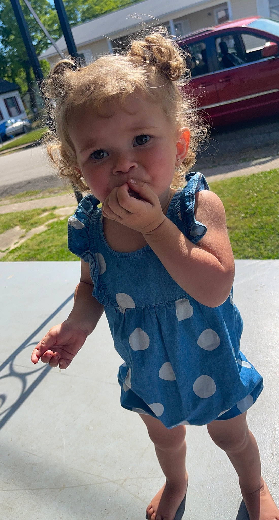 River is registered to the contest to win money with this photo: baby, baby_toddler_clothing, dress, facial_expression, finger, fun, gesture, grass, hair, hairstyle, happy, joint, one_piece_garment, person, photograph, plant, public_space, skin, sleeve, standing