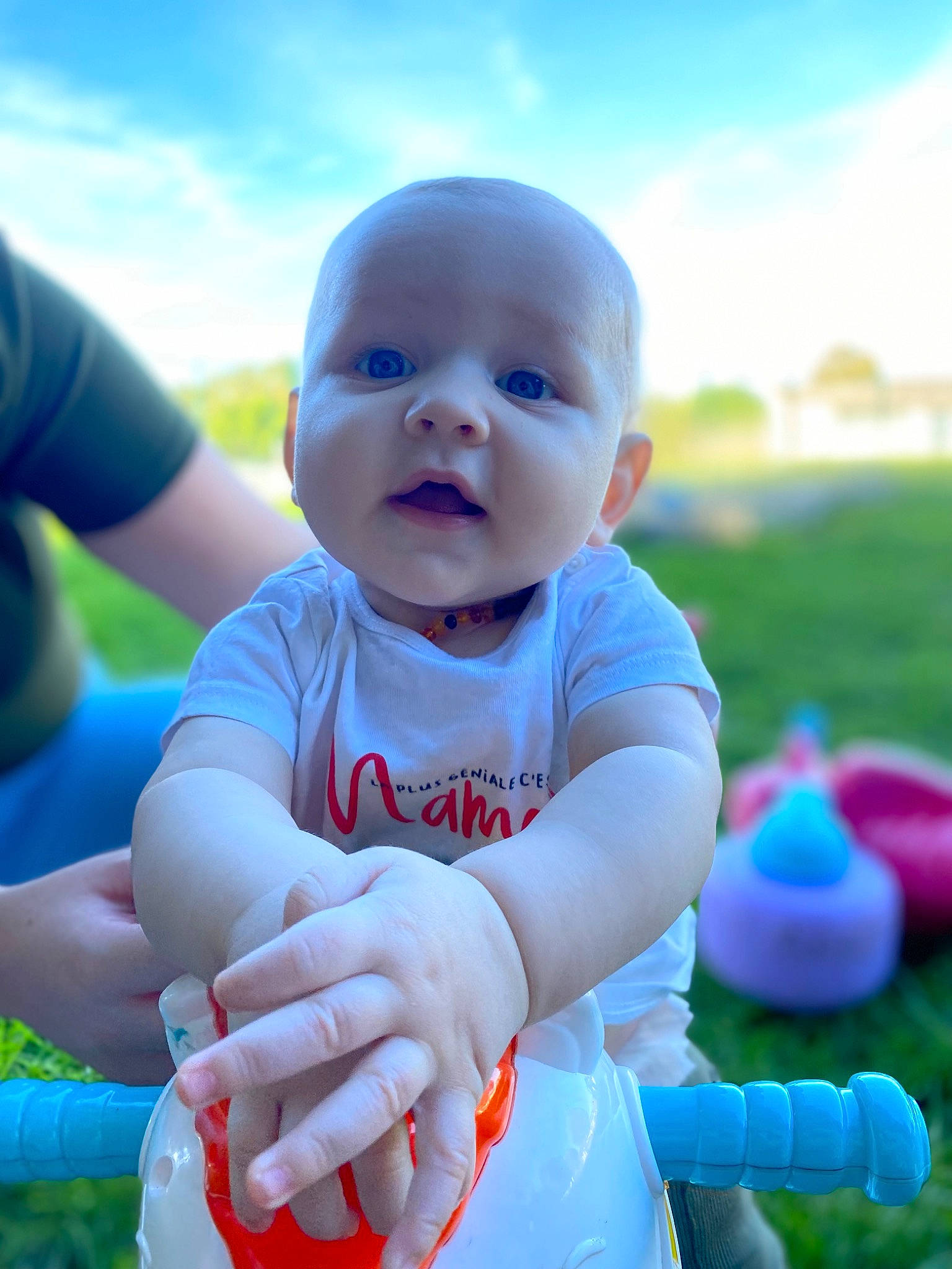 Timoteï a rejoint le concours — aidez-le/la à gagner de superbes lots ! azure, baby, baby_toddler_clothing, child, cloud, electric_blue, finger, fun, gesture, grass, happy, leisure, people_in_nature, person, pink, recreation, sitting, sky, smile, t_shirt