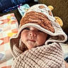 baby, child, blanket, hood, cute, face, smile, indoor, cozy, textile, pattern, soft, person, infant, wrapped, comfort, cute_outfit, baby_clothing, portrait, warm