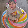 Penelope is registered to the contest to win money with this photo: baby, barefoot, child, colorful, cute, floor, grey_outfit, happy, headband, indoor, inflatable_ring, long_sleeve, person, pink_bow, playful, portrait, sitting, smiling, toddler, wooden_floor