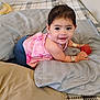 Penelope joined the competition — help win amazing prizes! baby, child, smiling, pink_clothing, bracelets, earrings, red_ball, pillows, bed, blanket, indoor, cute, happy, person, portrait, infant, lying_down, cozy, young_child, accessories