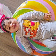 Penelope is registered to the contest to win money with this photo: baby, child, clothing, colorful, cute, floor, happy, headband, indoors, inflatable_ring, onesie, person, pink, playful, portrait, smiling, tigger, toddler, winnie_the_pooh, wooden_floor