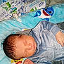 Michael is registered to the contest to win money with this photo: newborn, baby, sleeping, blanket, pacifier, blue_clothing, infant, soft_texture, shark_pattern, bedtime, cute, resting, face, hand, cozy, child, indoors, portrait, peaceful, young