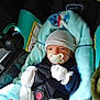 baby, car_seat, pacifier, blanket, mittens, hat, infant, child, seatbelt, clothing, comfort, indoor, cute, young_child, sitting, portrait, safety, soft_toy, warm, resting