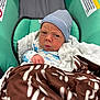 baby, infant, car_seat, blanket, hat, striped_hat, face, expression, wrapped, cozy, child, newborn, clothing, fabric, soft, indoor, person, cute, portrait, seated