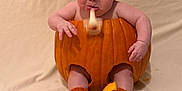 Ezra is registered to the contest to win money with this photo: baby, blanket, carved_pumpkin, costume, cute, drooling, expression, halloween, holiday, infant, knitted_booties, knitted_hat, legs, orange, portrait, prop, pumpkin, sitting, skin, studio