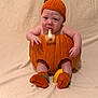 Ezra is registered to the contest to win money with this photo: baby, infant, pumpkin, costume, knitted_hat, knitted_booties, orange, carved_pumpkin, sitting, blanket, studio, cute, drooling, expression, prop, holiday, halloween, legs, skin, portrait