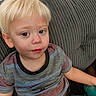 toddler, child, portrait, sitting, couch, indoors, blond_hair, blue_eyes, face, serious_expression, striped_shirt, shorts, arm, hand, furniture, upholstery, close_up, candid, home, photography