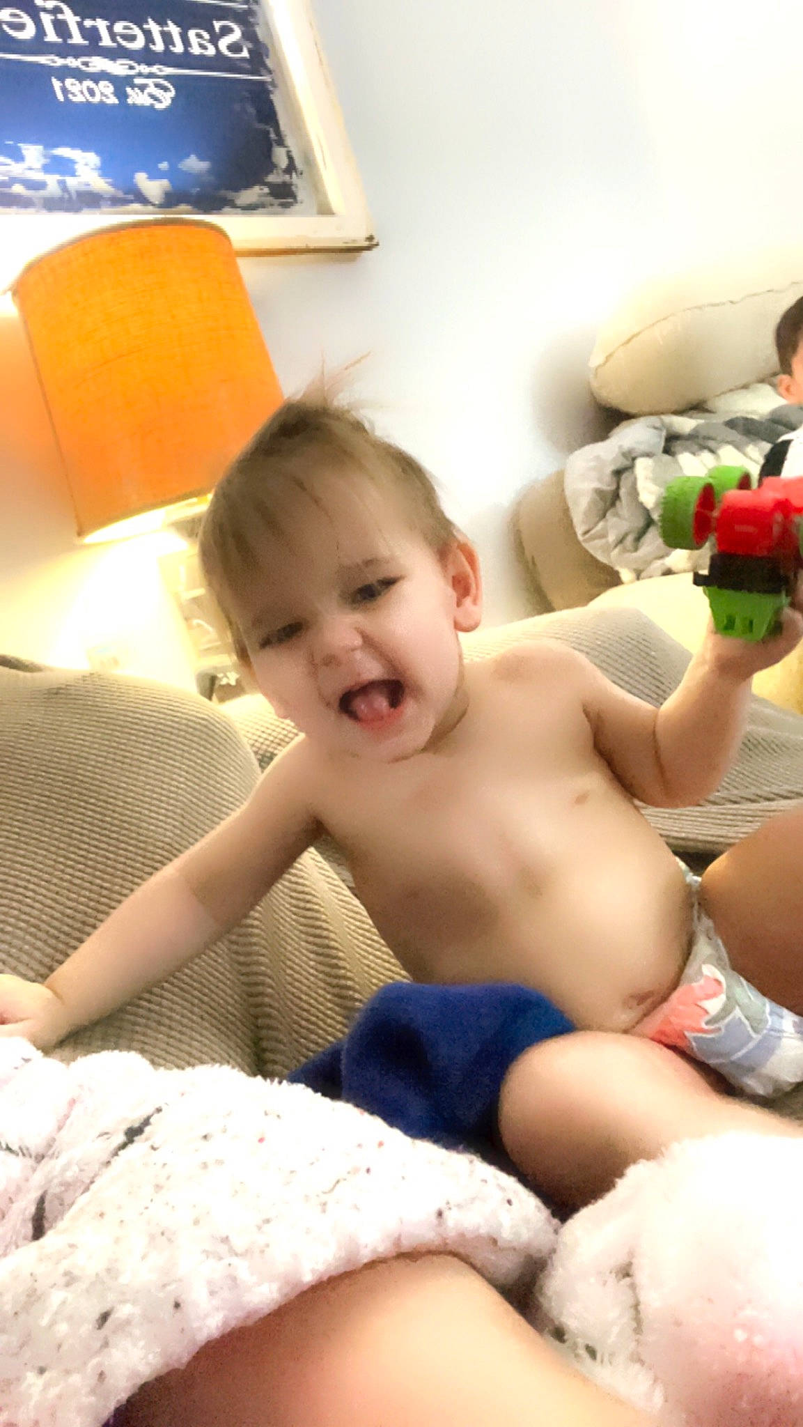 Corey is registered to the contest to win money with this photo: abdomen, baby, barechested, chest, child, comfort, finger, fun, happy, human_leg, knee, person, picture_frame, plant, room, rose, sitting, skin, thigh, toddler