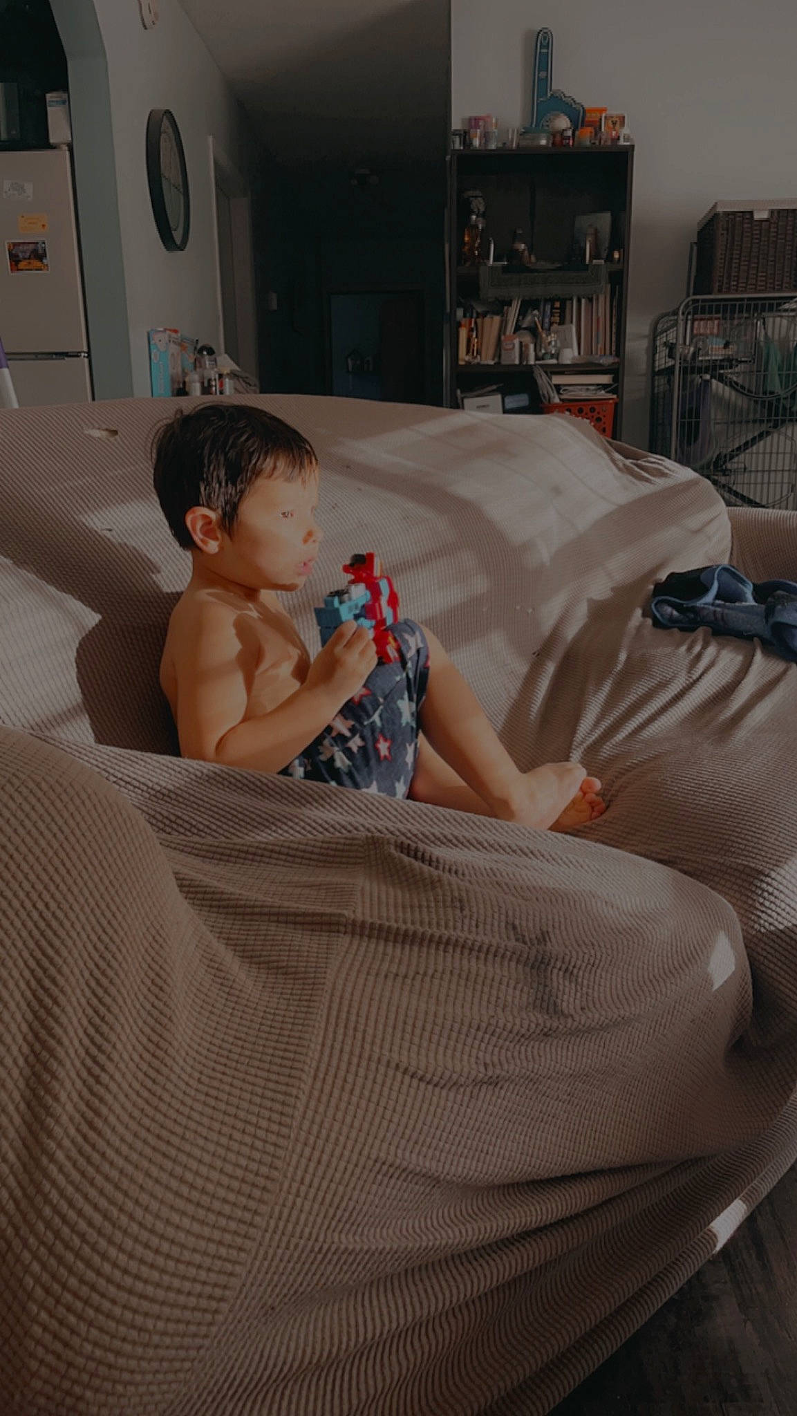 Koda is registered to the contest to win money with this photo: automotive_design, baby, bedding, bedroom, child, comfort, floor, flooring, fun, hardwood, human_leg, leisure, linens, living_room, person, picture_frame, room, sitting, textile, thigh