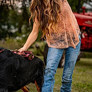 Atlas joined the competition — help win amazing prizes! woman, dog, leash, outdoor, grass, jeans, lace_top, smile, long_hair, brown_hair, casual_clothing, pet, playing, tractor, field, boots, nature, happy, young_adult, animal