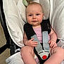 baby, infant, car_seat, safety_harness, plush_toy, blanket, cushion, child, cute, smiling, indoors, person, seat, sitting, comfort, soft, clothing, skin, hand, legs