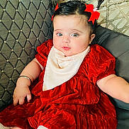 Sidak is registered to the contest to win money with this photo: baby, child, red_dress, pigtails, red_bows, bib, couch, toy, pink_toy, face, smiling, indoor, cute, chubby_cheeks, person, sitting, happy, bright_eyes, furniture, plush