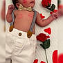 Hans is registered to the contest to win money with this photo: baby, infant, face, bow_tie, suspenders, white_pants, red_hearts, rose, kiss_marks, cute, lying_down, soft_surface, portrait, hand, skin, dark_hair, expressive_eyes, valentine_theme, adorable, decorative