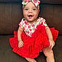 Kali is registered to the contest to win money with this photo: baby, child, smile, happy, red_dress, headband, strawberry_pattern, couch, sitting, cute, infant, clothing, portrait, face, hands, legs, indoor, bright_eyes, joyful, adorable