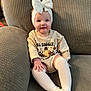 Paisley is registered to the contest to win money with this photo: baby, child, bow, headband, socks, couch, smile, clothing, infant, person, sitting, cute, happy, indoors, portrait, textile, knitwear, young_child, fashion, cozy