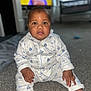 baby, child, pajamas, carpet, floor, drool, indoor, face, person, sitting, clothing, cute, home, infant, looking, young_child, portrait, hands, feet, television