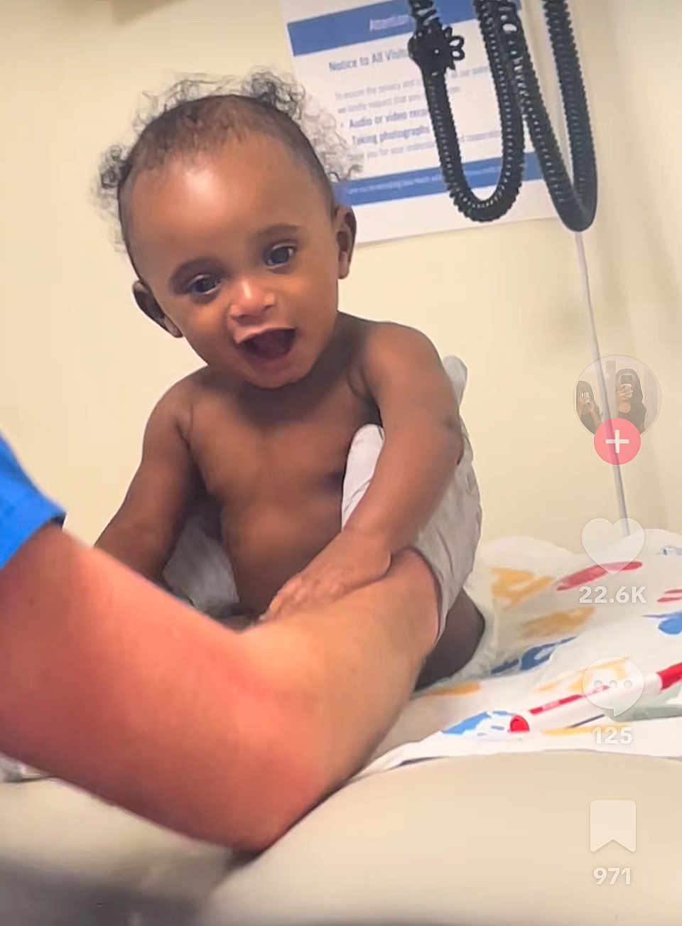 Jaylen joined the competition — help win amazing prizes! baby, child, smiling, happy, curly_hair, diaper, arm, adult_hand, medical_equipment, clinic, examination_table, notice, person, indoor, healthcare, skin, expression, holding, playful, cute