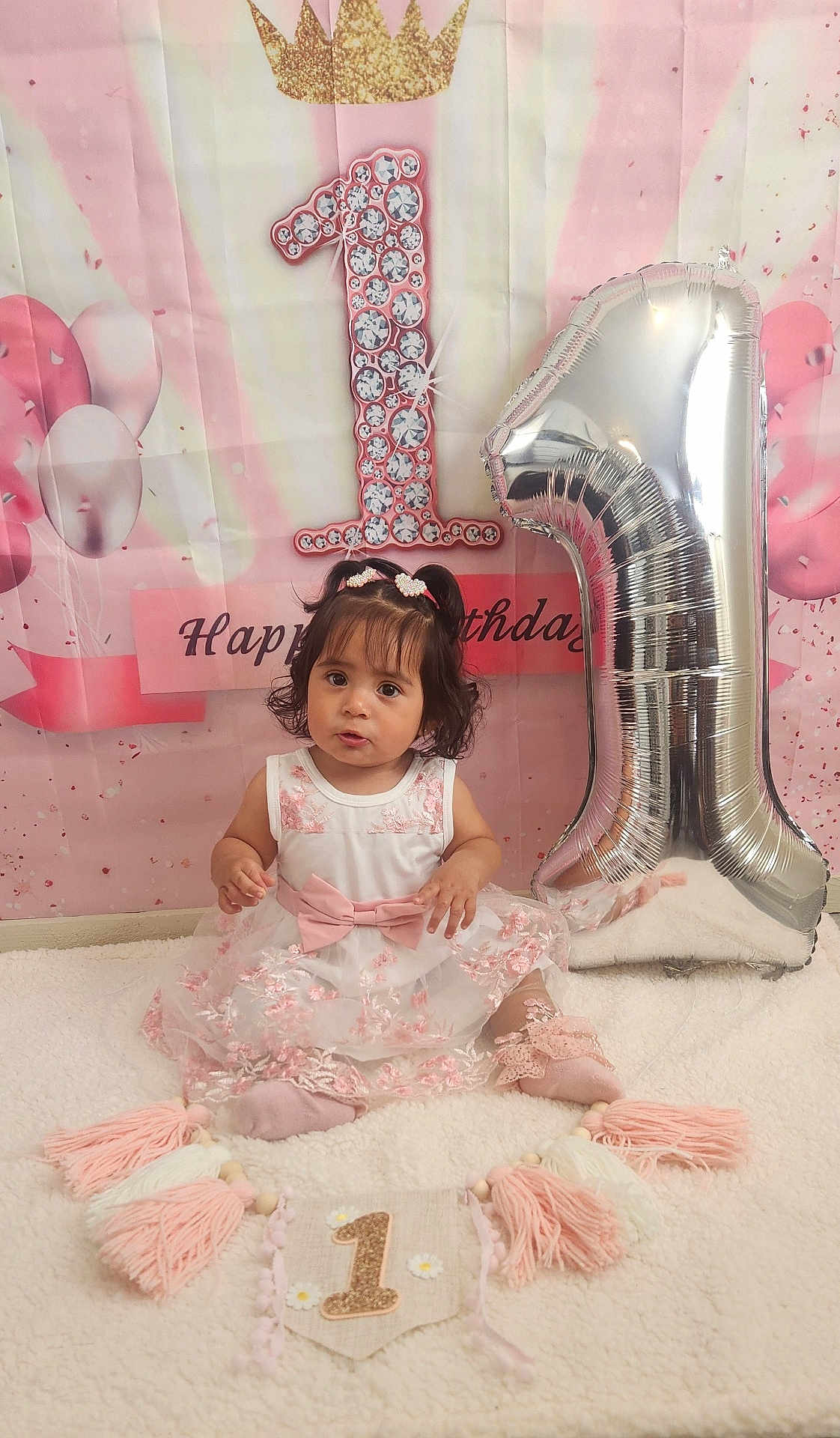 Juliette is registered to the contest to win money with this photo: toddler, birthday, balloon, number_one, dress, pink, white, hair_clips, sitting, blanket, decorations, celebration, child, portrait, cute, indoors, smile, face, party, soft