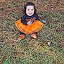 toddler, child, smiling, orange_tutu, black_shirt, grass, pine_needles, pine_cones, outdoor, nature, happy, sitting, fall, cute, hair_clip, brown_shoes, person, young_child, festive_clothing, joy