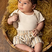 Mateo a rejoint le concours — aidez-le/la à gagner de superbes lots ! baby, infant, child, hat, striped_clothing, knitted_toy, teddy_bear, wooden_bowl, yellow_wool, curious, cute, portrait, indoors, soft_light, plush, relaxing, small_hands, barefoot, cozy, adorable