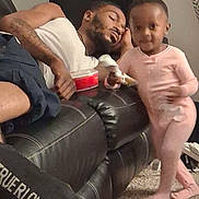 Giovanna is registered to the contest to win money with this photo: black, carpet, casual, child, couch, family, furniture, home, indoor, leather, living_room, man, pajamas, person, pink, relaxing, resting, sleeping, toddler, toy