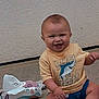 baby, child, smiling, yellow_tshirt, shark_graphic, wipes, grass, outdoor, concrete, wall, sitting, happy, toddler, footwear, cute, infant, person, shorts, sock, playful