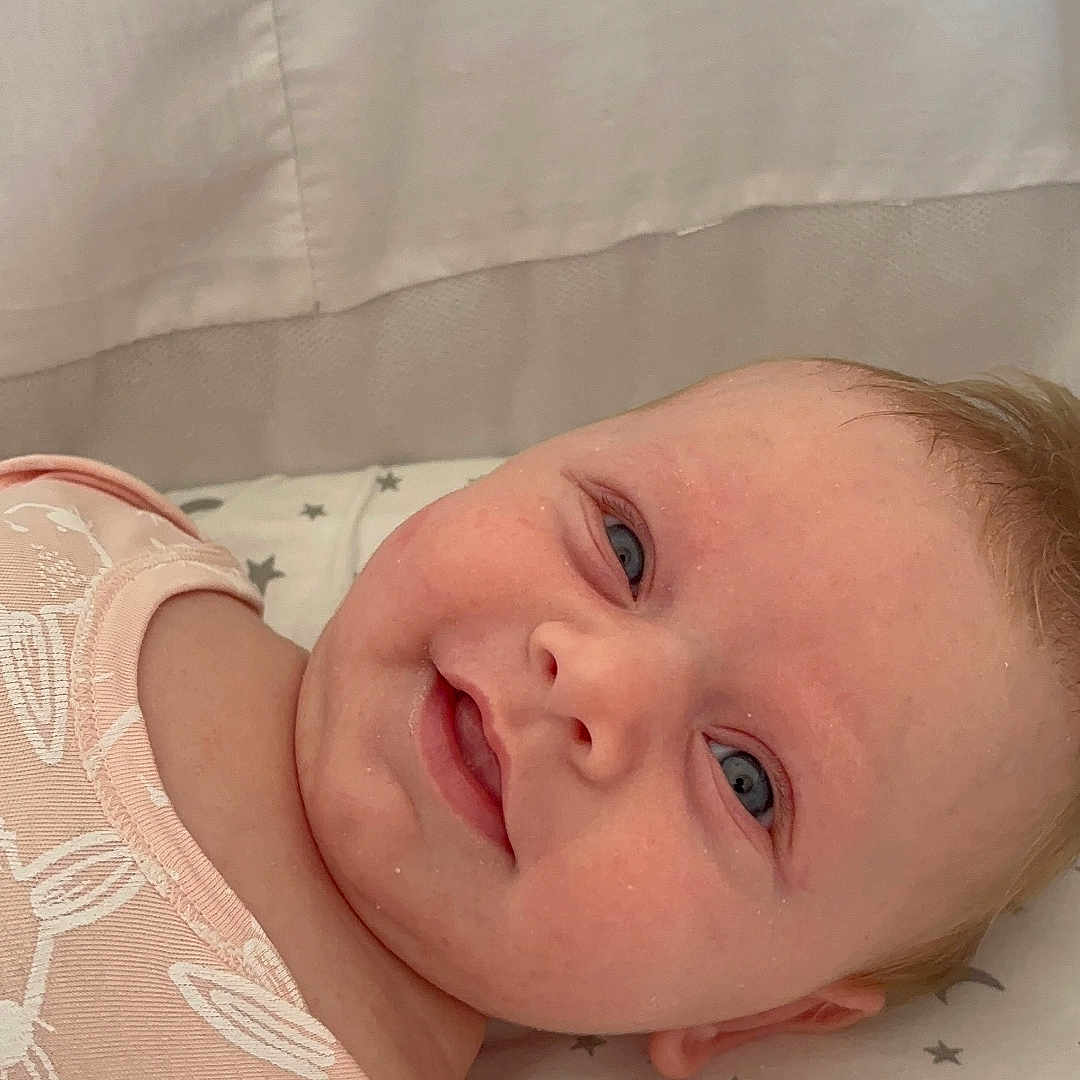 Leia-May is registered to the contest to win money with this photo: adorable, baby, blanket, blue_eyes, bunny_pattern, cheeks, child, closeup, cute, face, head, indoor, infant, lying_down, moon, pink_clothing, skin, smile, soft_light, stars