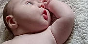 Paxton is registered to the contest to win money with this photo: arm, baby, blanket, child, closeup, curious, expression, face, hand, indoors, infant, lying_down, natural_light, newborn, peaceful, portrait, resting, skin, soft, texture