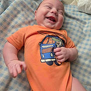 Paxton joined the competition — help win amazing prizes! baby, blanket, blue_checkered, cartoon_print, child, clothing, cute, expression, face, hand, happy, indoor, infant, joy, lying_down, mouth_open, orange_shirt, person, smiling, soft_texture