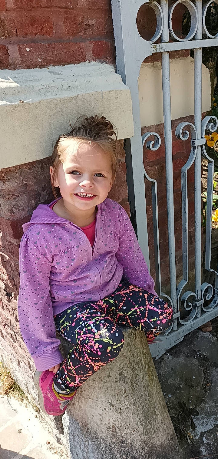 Inès participe au concours pour gagner de l'argent avec cette photo : baby_toddler_clothing, blond, child, clothing, eye, happy, head, home_fencing, joy, leisure, magenta, musical_instrument, person, picket_fence, pink, purple, sleeve, smile, standing, textile