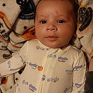 Fenix is registered to the contest to win money with this photo: baby, infant, onesie, blanket, halloween, pattern, face, portrait, child, cute, lying_down, clothing, indoor, cozy, soft_texture, young_child, expression, looking_at_camera, sleepwear, toddler