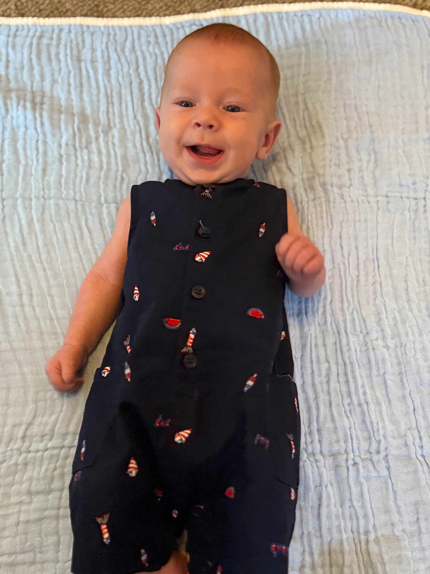 Kash is registered to the contest to win money with this photo: baby, smiling, infant, blue_blanket, navy_outfit, rocket_pattern, watermelon_pattern, lying_down, happy, cute, child, one_person, indoors, textured_blanket, clothing, portrait, small_child, human, baby_clothes, joyful