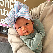 Lucia joined the competition — help win amazing prizes! baby, infant, child, headwear, bow, onesie, floral_pattern, person, face, eyes, hands, arm, clothing, indoor, holding, portrait, newborn, cute, warm_colors, home