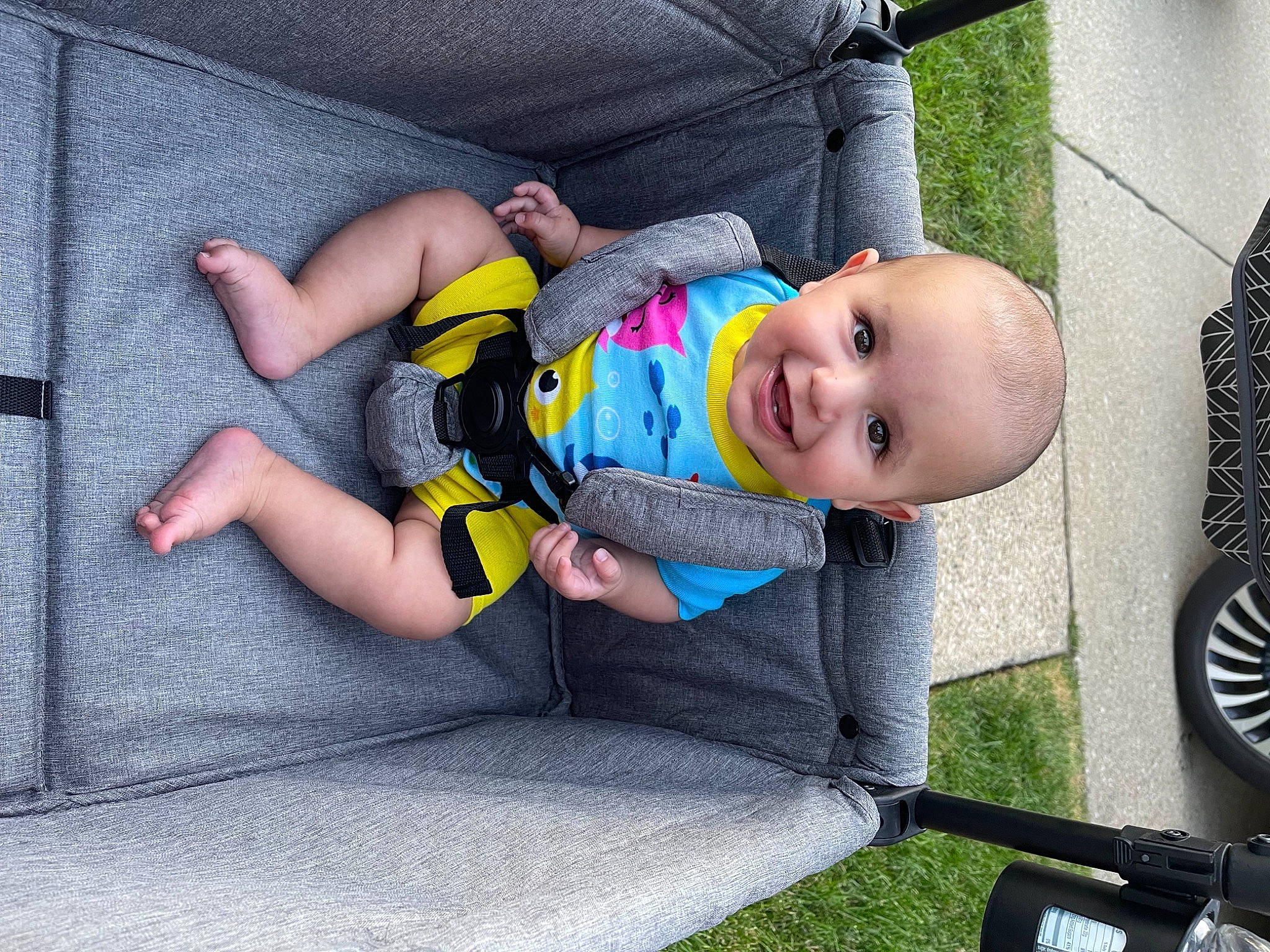 Hassan is registered to the contest to win money with this photo: auto_part, baby, baby_carriage, baby_laughing, baby_products, baby_safety, baby_toddler_clothing, child, comfort, face, facial_expression, flooring, fun, grass, head, joy, mechanical_fan, person, sitting, smile