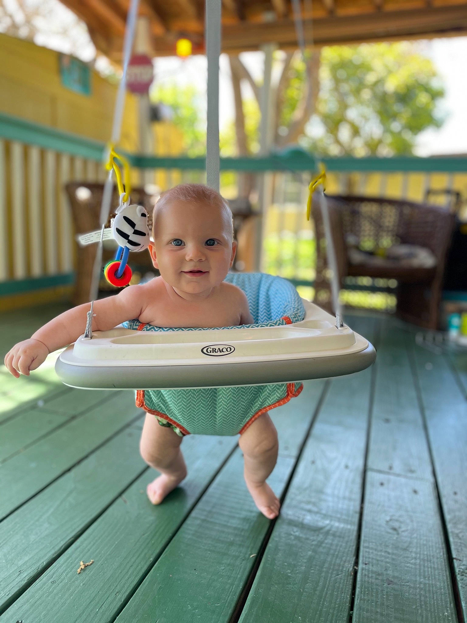 Zane is registered to the contest to win money with this photo: barefoot, child, deck, foot, fun, grass, happy, joy, leisure, nonbuilding_structure, outdoor_furniture, person, play, recreation, sitting, smile, summer, swing, t_shirt, toddler